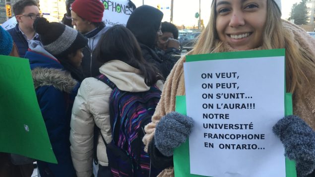Une jeune fille tient une pancarte réclamant une première université francophone en Ontario