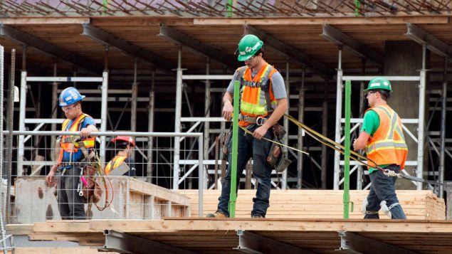 Des travailleurs s'affairent à construire un immeuble à Montréal.