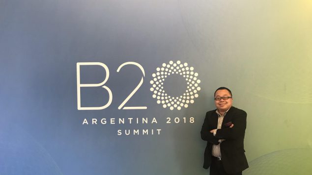 Winston Chan pose devant le logo du B20 en Argentine