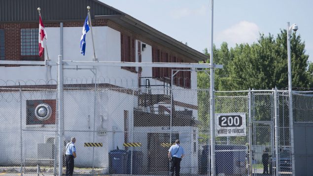 Des gardes se tiennent devant les portes d'un centre de rétention d'immigrants à Laval, au Québec, le lundi 15 août 2016. Photo : La Presse Canadienne / Graham Hughes