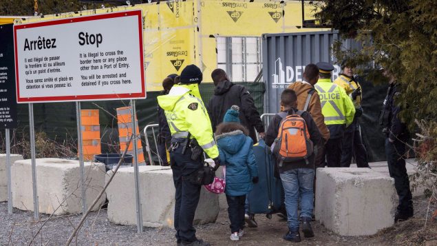 Une famille de demandeurs d’asile arrêtée par des agents de la GRC alors qu'elle traverse la frontière entre le Canada et les États-Unis près de Champlain, dans l'État de New York, le 18 avril 2018. Photo : La Presse Canadienne / Paul Chiasson