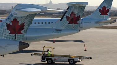 Aviones de Air Canada esperan en su puerta de embarque respectiva en el aeropuerto internacional de Montreal, el tercero en importancia de Canadá. Se percibe en el fondo la silueta de la montaña Mont-Royal, detrás de la cual se encuentra el centro de la ciudad de Montreal.   (Ryan Remiorz/Canadian Press) 