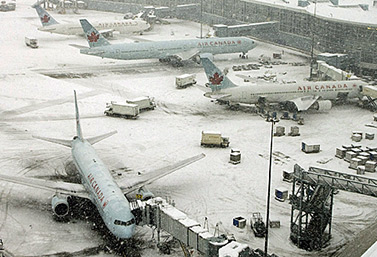 Aviones de Air Canada, cubiertos de nieve, esperan la señal para hacer abordar los pasajeros, en Toronto.   (Richard Lam/Canadian Press) 