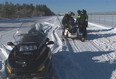 Una pista de motos de nieve en Quebec, con motivo de la Semana Internacional de la Seguridad de este tipo de vehículos. Se puede ver a los agentes del orden que entregan un papel de instrucciones a los conductores de las motos de nieve. (Radio-Canada) 