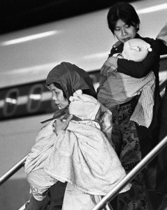 Des femmes réfugiées vietnamiennes transportent des enfants hors de l'avion à l’aéroport de Dorval 26 novembre 1978. LA PRESSE CANADIENNE / John Goddard
