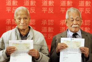 Thomas Soon (left) 97-years-old and Charlie Quon, 99-years-old, hold government cheques, the first redress payments to Chinese Head Tax payers in Vancouver Friday October 20, 2006. (CP P HOTO/Lyle Stafford)