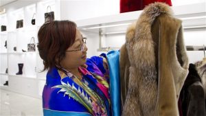 Dans le magasin Always in Vogue de Shenyang, une cliente examine un manteau en peau de phoque. PHOTO : ICI RADIO-CANADA/PHILIPPE GRENIER