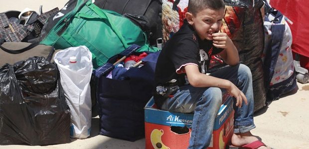 Un jeune garçon réfugié syrien est assis à côté de sacs à son arrivée au poste frontière de la ville irakienne de Qaim, à 320 kilomètres à l'ouest de Bagdad, en Irak. (Hadi Mizban / Associated Press)