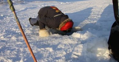 An Inuit hunter peers into a hole in the ice to check his fishing nets. Photo by Levon Sevunts.