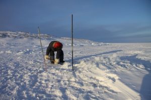 Un chasseur inuit utilise une pelle pour retirer la neige fondante qui s’est formée sur le trou où ses filets sont tendus. Photo Levon Sevunts.