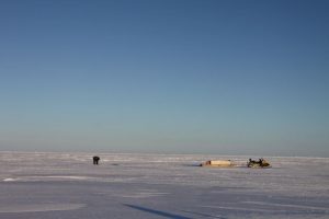 Un chasseur inuit se tient debout au-dessus d’un trou d’air sur la mer glacée. Photo Levon Sevunts.