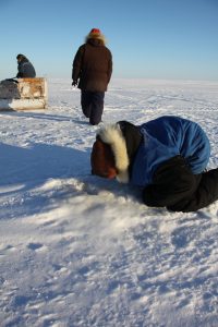 Un jeune chasseur inuit regarde dans un trou d’air qu’utilisent les phoques pour respirer sous la mer glacée près de Clyde River, au Nunavut. Photo Levon Sevunts.