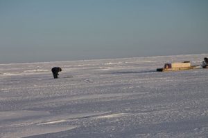 Un chasseur inuit se tient debout au-dessus d’un trou d’air sur la mer glacée. Photo Levon Sevunts.