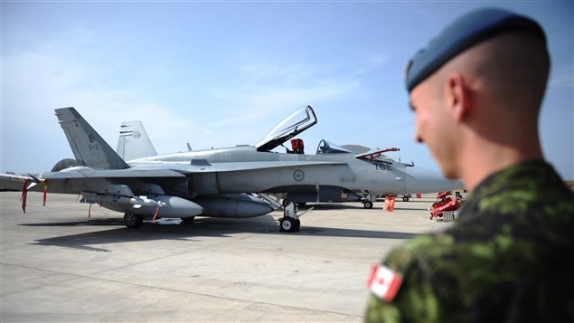 Un soldat canadien observe un CF-18 (archives) (Sean Kilpatrick / La Presse Canadienne)