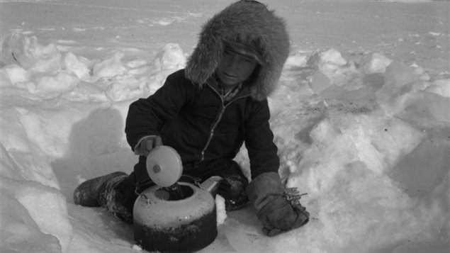 Petit garçon qui cherche de l’eau à l’aide d’une bouilloire à Brochet au Manitoba Crédit photo : Bibliothèque et Archives Canada