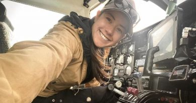 Une femme sourie à la caméra à l'intérieur d'une cabine de pilote.