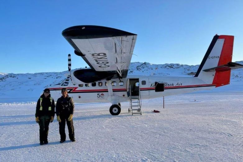 Deux pilotes se tiennent debout devant un avion, sur le tarmac de l'aéroport de Kimmirut, au Nunavut, en mars 2023.