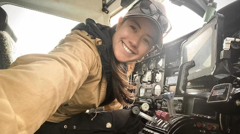 Une femme sourie à la caméra à l'intérieur d'une cabine de pilote.