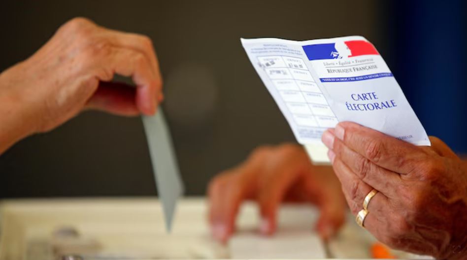 Une personne tient un bulletin de vote français.