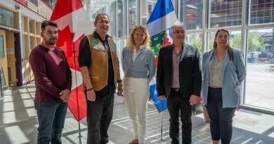 Cinq personnes se tiennent devant les drapeaux du Canada et des Territoires du Nord-Ouest