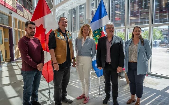 Cinq personnes se tiennent devant les drapeaux du Canada et des Territoires du Nord-Ouest