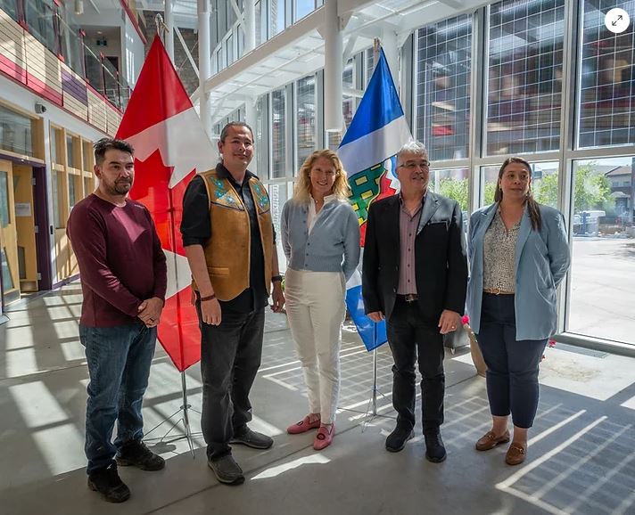 Cinq personnes se tiennent devant les drapeaux du Canada et des Territoires du Nord-Ouest