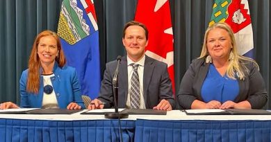 Trois personnes assises regardent la caméra en souriant, derrière un micro