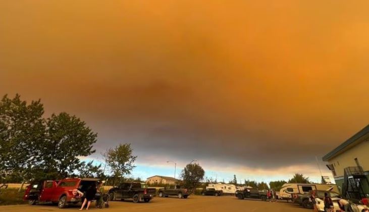 Des voitures se préparent à partir, dans un ciel orange de fumée.