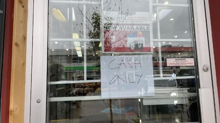 Un commerce ayant une affiche « argent comptant seulement »