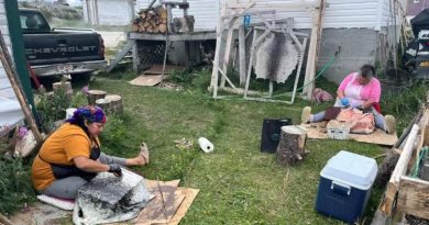 Deux femmes sont assises dans l'herbe et préparent des peaux de phoque à la main, à Hopedale, au Nunatsiavut.
