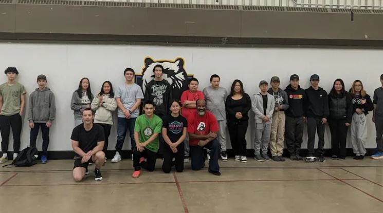Une vingtaine de personnes se tiennent debout devant un mur dans le gymnase d'une école de Kulguktuk, au Nunavut, le 12 septembre 2024.