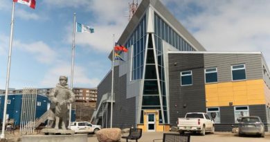 Des drapeaux volent dans le vent devant le bâtiment extérieur du détachement de la Gendarmerie royale du Canada (GRC) à Iqaluit, au Nunavut, en été.