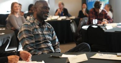 Jean de Dieu Tuyishime est assis à une table, souriant, de profil, le 21 septembre 2024 à Yellowknife.