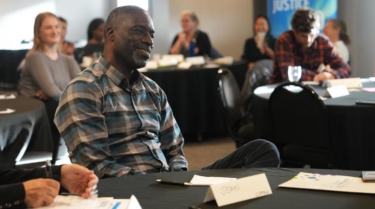 Jean de Dieu Tuyishime est assis à une table, souriant, de profil, le 21 septembre 2024 à Yellowknife.