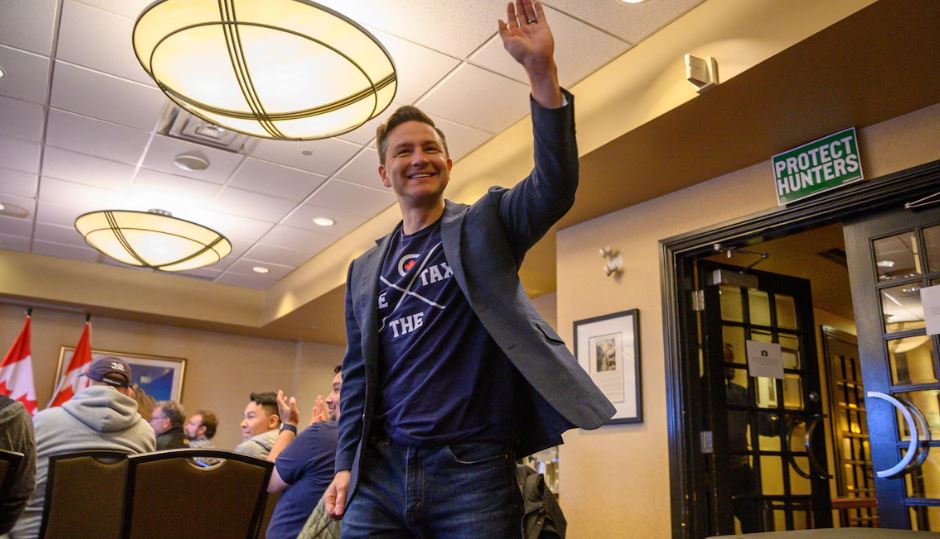 Le chef du Parti conservateur, Pierre Poilievre, lève la main vers le ciel en souriant, dans une salle de conférence, à l'hôtel Frobisher Inn d'Iqaluit, le 9 septembre 2024.