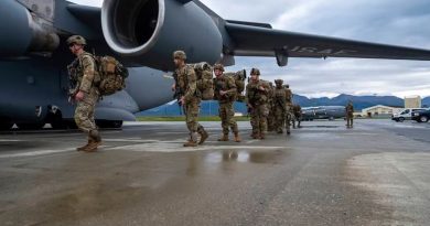 Des soldats en ligne entrent, un après l'autre, dans un avion gros porteur militaire.