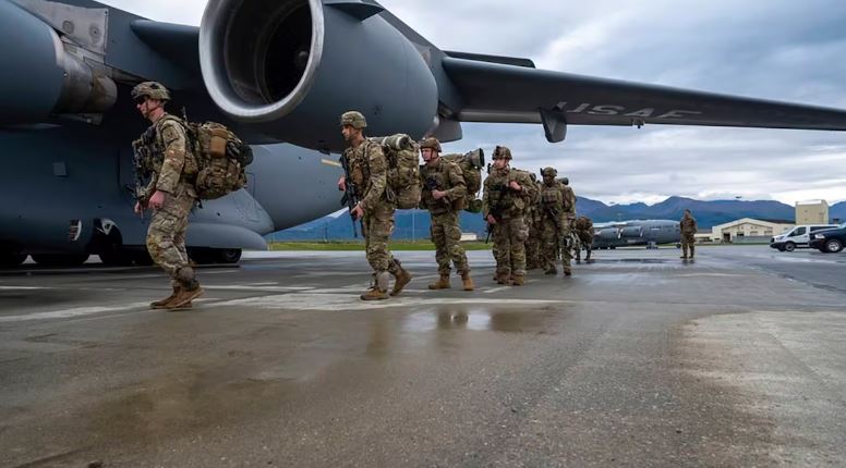 Des soldats en ligne entrent, un après l'autre, dans un avion gros porteur militaire.