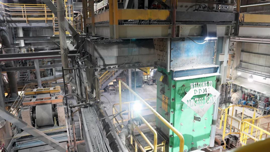 Une plaque de métal découpée pour indiquer «Welcome to DDMI Process Plant» est apposée sur le mur à l'intérieur de l'usine.