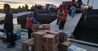 Des résidents de Whale Cove, au Nunavut, transportent des boîtes de carton sur le quai.