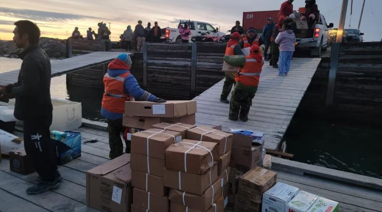 Des résidents de Whale Cove, au Nunavut, transportent des boîtes de carton sur le quai.