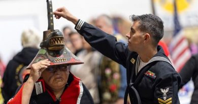Un soldat touche un chapeau d'une madame autochtone.