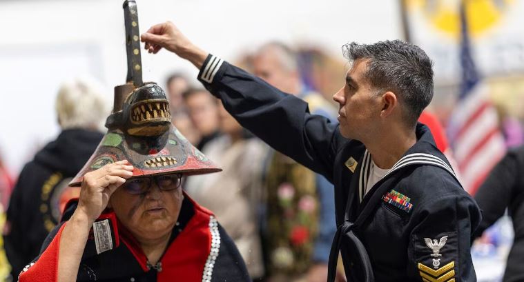 Un soldat touche un chapeau d'une madame autochtone.