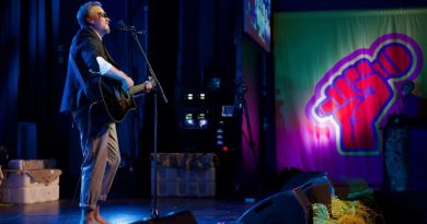 Un chanteur dont les yeux sont peints en noir chante dans un micro en jouant de la guitare sur la scène du Centre culturel Katuaq, à Nuuk, au Groenland.