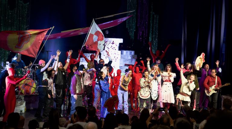 Une trentaine de personnes sont réunies sur la scène du Centre culturel Katuaq et lancent des confettis tout en brandissant des drapeaux.