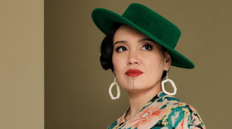Une femme vêtue d'un chapeau vert regarde sur le côté.