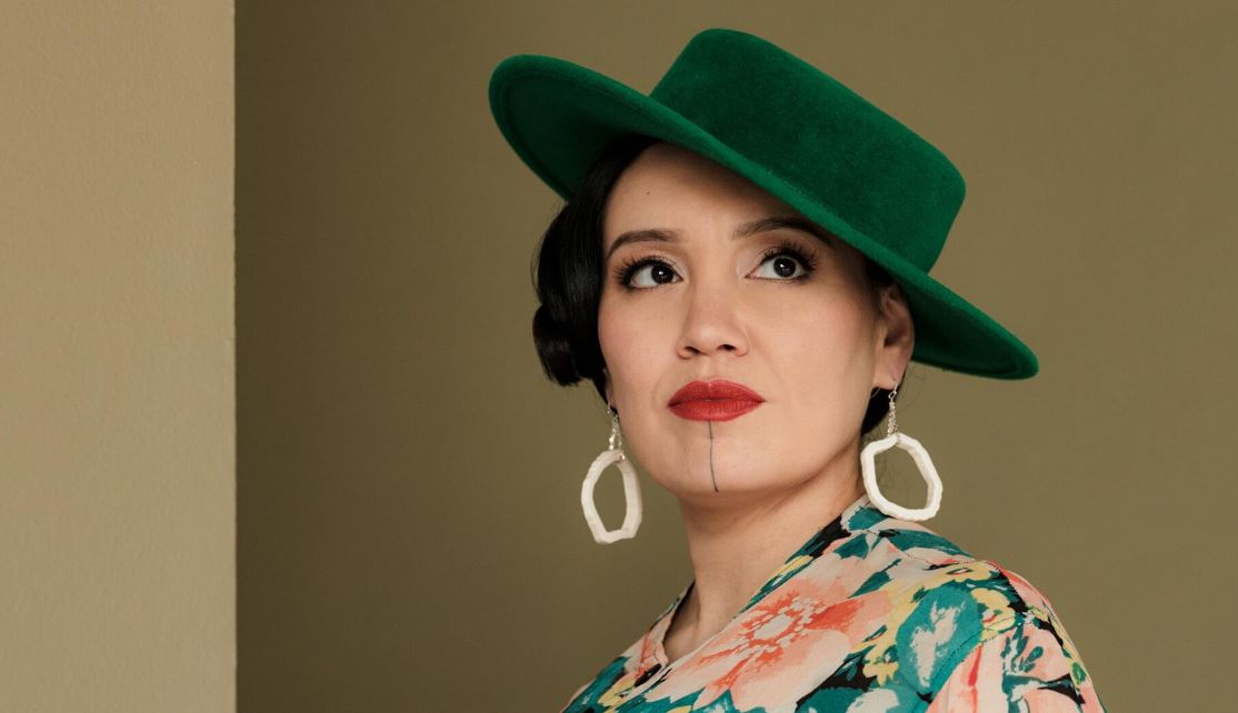 Une femme vêtue d'un chapeau vert regarde sur le côté.