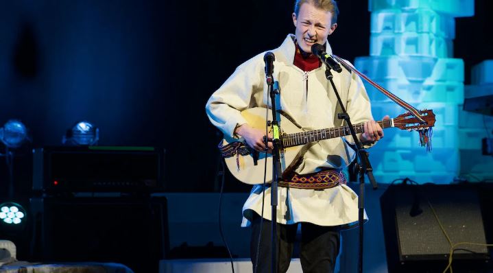 Un artiste chante dans un micro en jouant de la guitare sur la scène du Centre culturel Katuaq, le 13 octobre 2024.