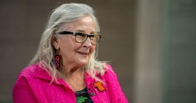 Marie Wilson porte une veste rose, des boucles d'oreilles perlées et une broche symbolisant un chandail orange pour la journée de commémoration des survivants de pensionnats pour Autochtones.