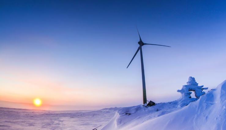Une éolienne sur un sol enneigé.
