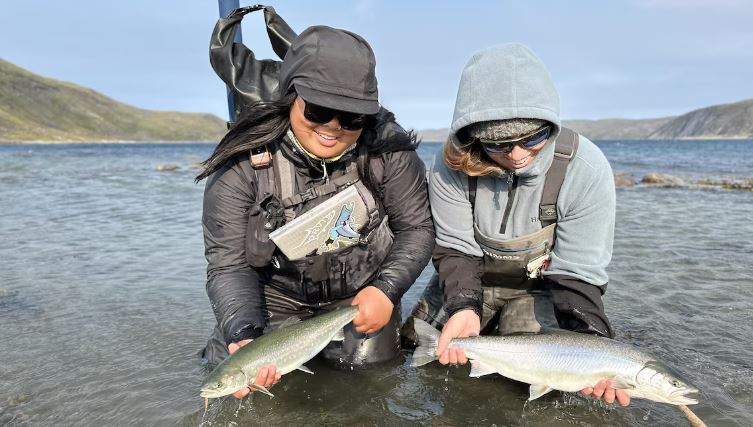 Deux pêcheuses tiennent des ombles de l'Arctique.